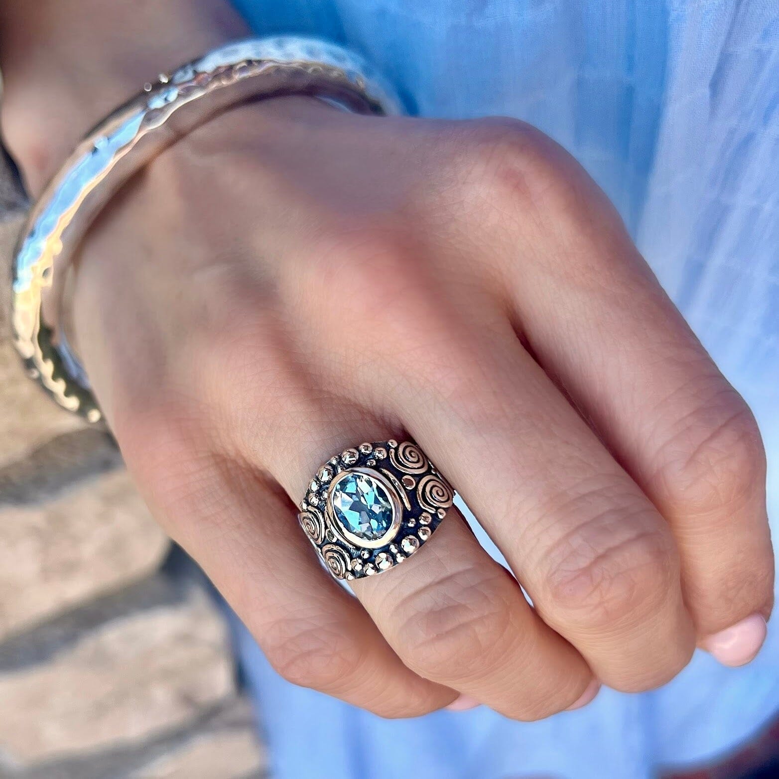 wide designer silver ring featuring oval shaped blue topaz and oxidiation on the band