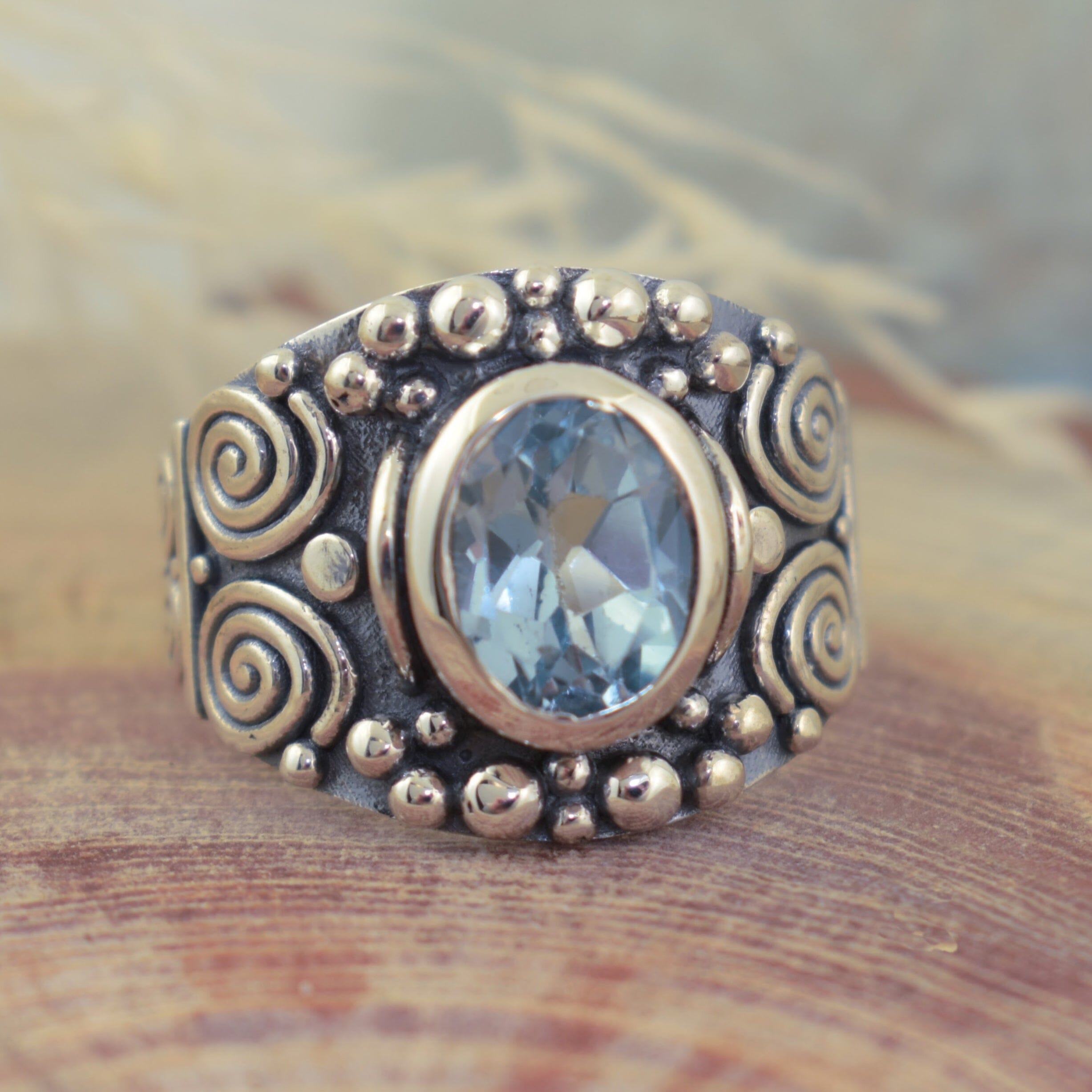 Whimsical sterling silver wide band ring with oval shaped blue topaz center