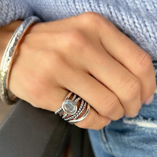 wide silver pinky ring featuring bezel set labradorite on several thin bands with designs