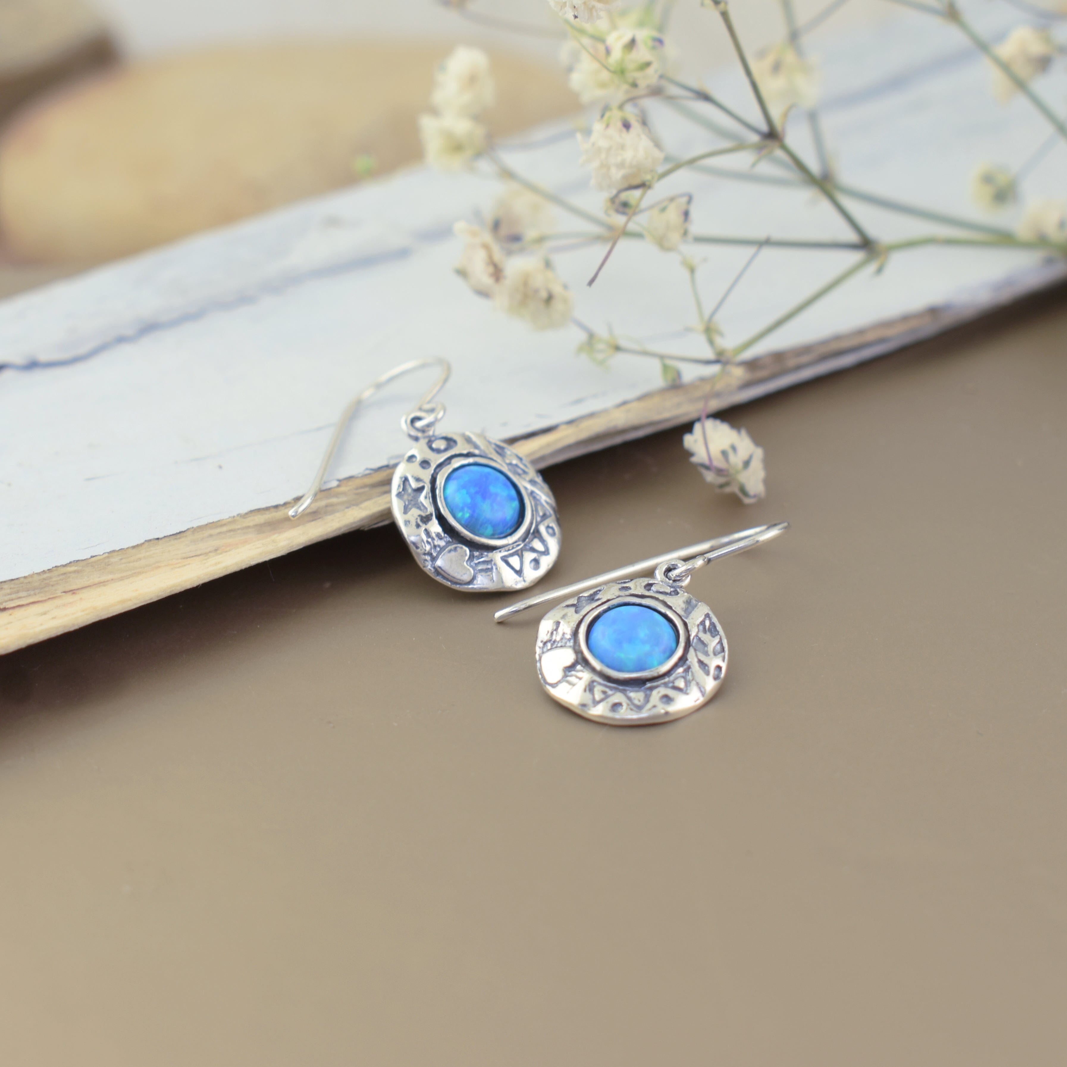 round sterling silver dangling earrings featuring a reconstructed opal center with star and heart designs