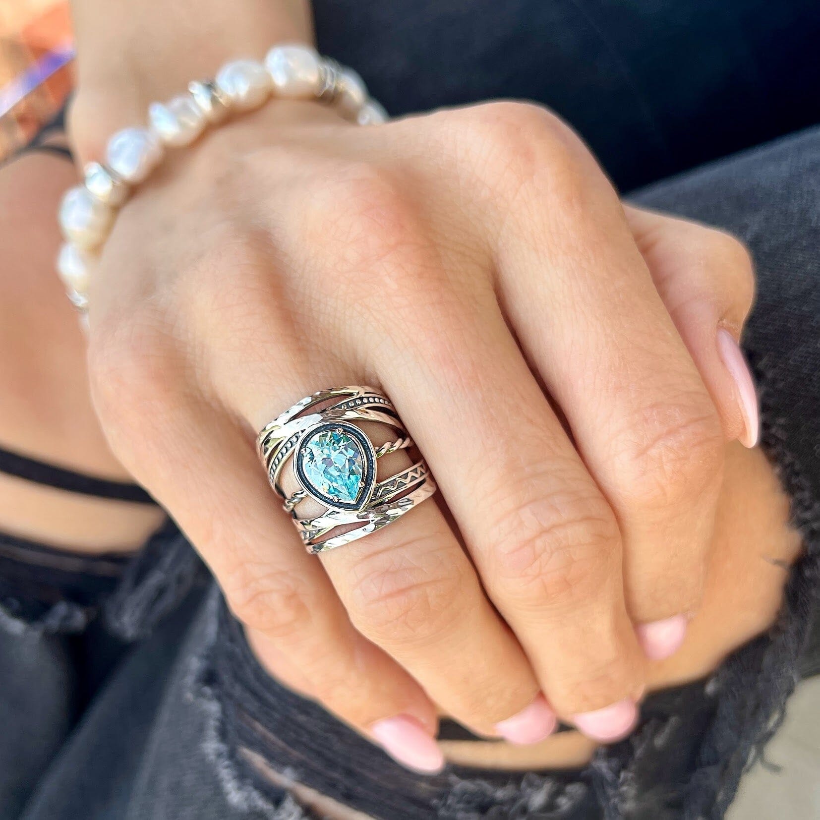 wide sterling silver ring with a pear-shaped prong-set sky blue cubic zirconia center