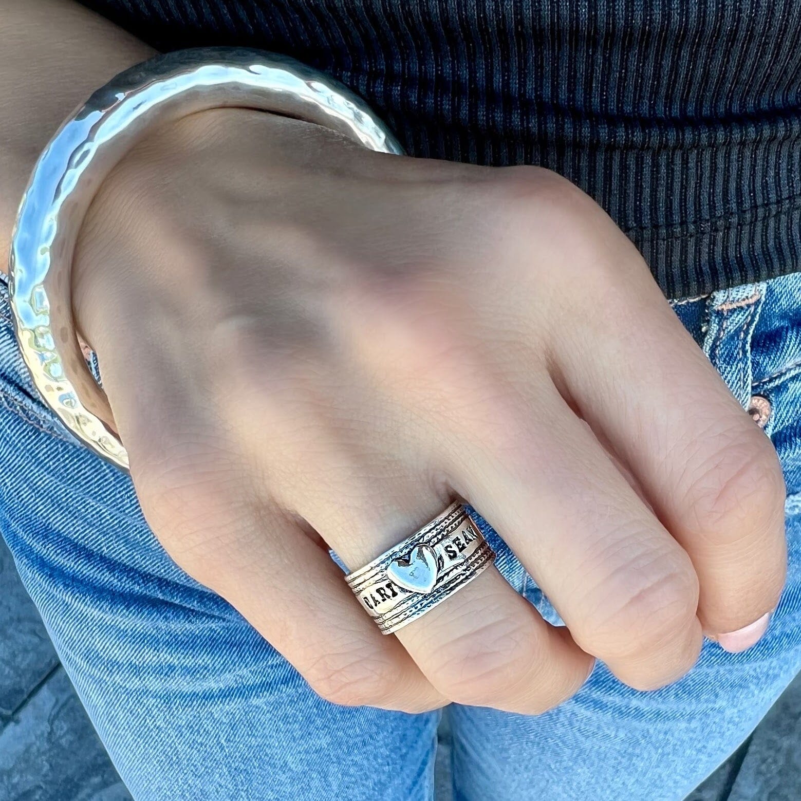 wide personalized ring featuring two hand-stamped names with a silver heart center