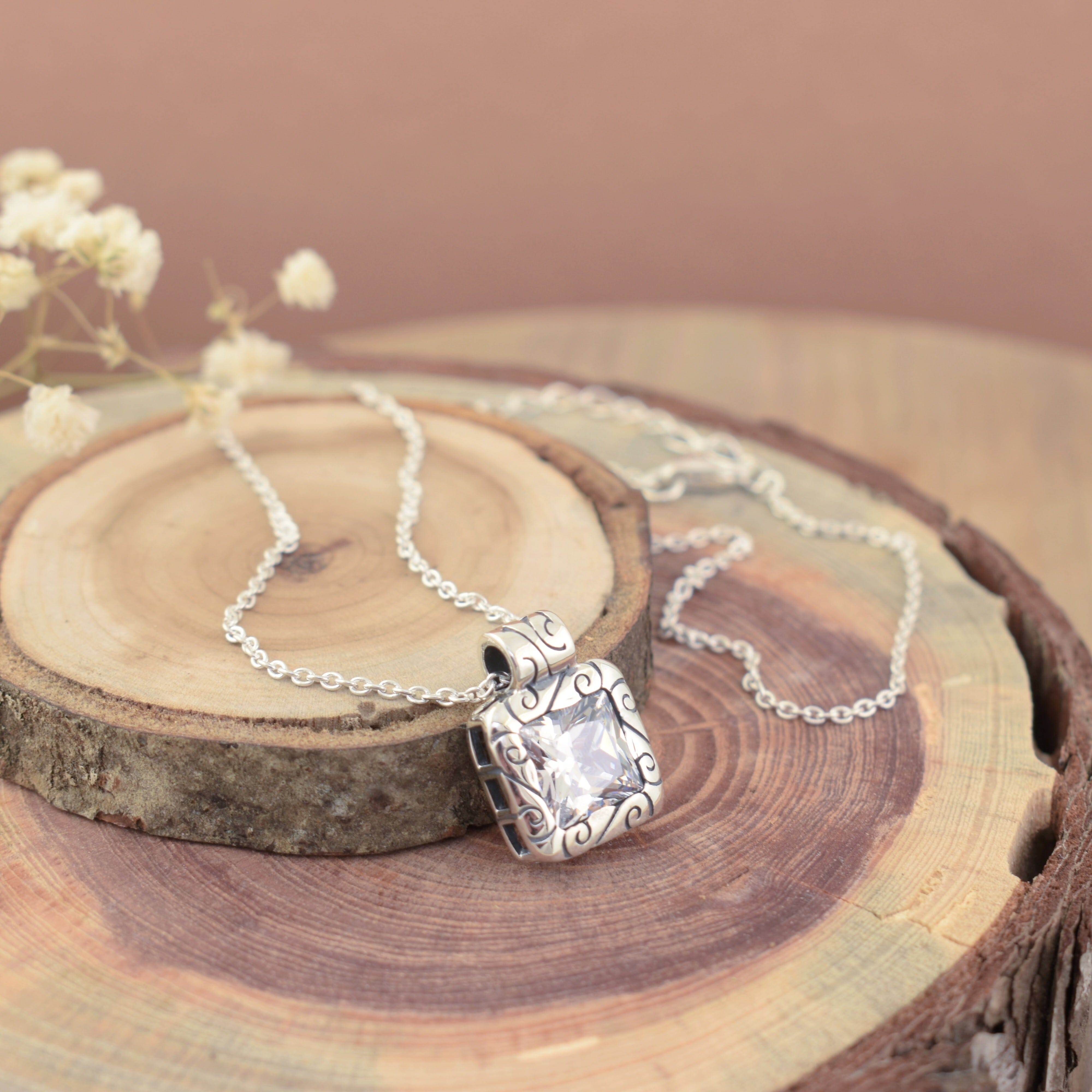 sterling silver necklace featuring a square shaped princess cut cubic zirconia bezel set in a filigree detailed pendant